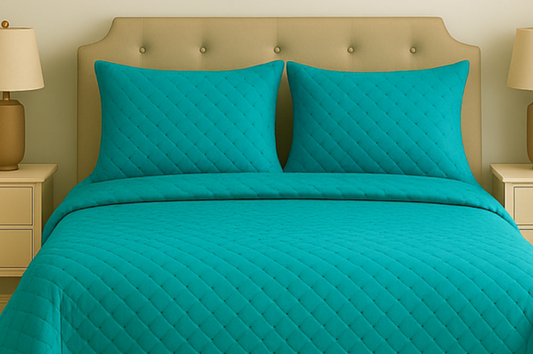 Turquoise quilted bedding set on a bed with matching pillows, against a neutral bedroom background.
