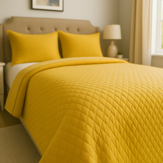Yellow quilted cover and pillows on a bed in a bedroom setting.
