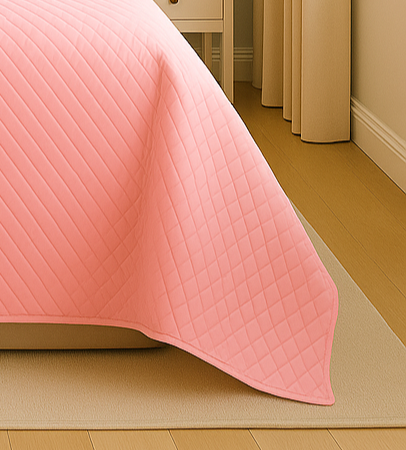 Pink quilted blanket on a bed with beige curtains in the background